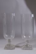 A PAIR OF GLASS HURRICANE LAMPS on square bases. 13ins high.