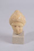 A SMALL ROMAN CARVED MARBLE BUST OF A WOMAN. 3ins high, on a square marble base.