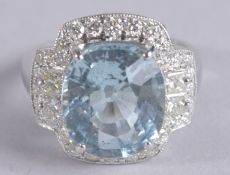 AN 18CT WHITE GOLD DRESS RING SET WITH A LARGE OVAL CUSHION AQUAMARINE surrounded by princess cut