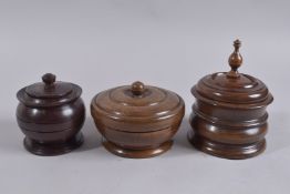 THREE TREEN CIRCULAR TOBACCO JARS AND COVERS.