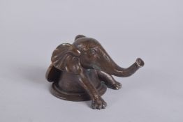 A BRONZE ELEPHANT DESK WEIGHT, on a circular base. 3.5ins diameter.