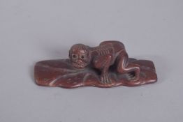 A CARVED WOOD MONKEY ON A BRANCH. 4ins, signed.