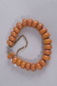 A STRING OF TWENTY-THREE AMBER TYPE BEADS. Each bead 2.25cms.