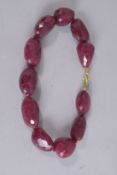 A NECKLACE set with eleven facet ruby stones. 22ins long.