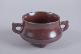 A CHINESE OX BLOOD TWIN HANDLE TRIPOD CENSER, base with character mark, 17cm wide handle to handle.