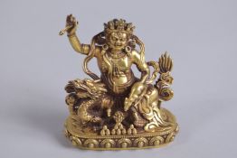 A TIBETAN GILT ALLOY FIGURE OF A DEITY, inscribed to reverse, 10cm high.
