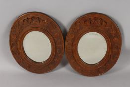 A PAIR OF CHINESE CARVED SANDALWOOD OVAL MIRRORS, the frames ornately carved with foliate border