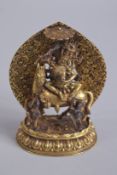 A TIBETAN GILT ALLOY MAHAKALA DEITY ON HORSEBACK, the reverse with detachable halo and