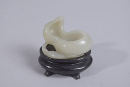 A 19TH CENTURY CHINESE JADE CARVING ON HARDWOOD STAND, 5cm wide.