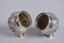 A PAIR OF 19TH CENTURY SOUTH INDIAN MADRAS SILVER SALT CELLARS, with embossed hindu gods.