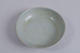 A CHINESE CELADON GLAZE SAUCER, 14cm diameter.