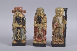 THREE 20TH CENTURY CHINESE CARVED AND PAINTED SOAPSTONE IMMORTALS, each approx. 20cm high.