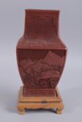 A CHINESE RED CINNABAR LACQUER VASE ON WOODEN STAND, with landscape scenes and flora, 28cm high.