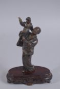 A JAPANESE MEIJI PERIOD SHIBAYAMA BRONZE OKIMONO, of a robed man holding a child aloft, standing