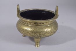 A CHINESE ENGRAVED BRASS TRIPOD CENSER, the base with character mark, 11.5cm wide.