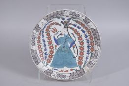 A TURKISH OTTOMAN IZNIK STYLE GLAZED POTTERY DISH, painted with figure, 30.5cm diameter.