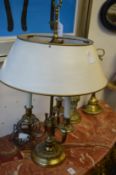 A brass three branch table lamp with toleware style shade.