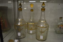 A pair of 19th century gilt decorated cut glass decanters and stoppers together with another