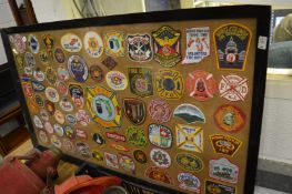 A large framed and glazed collection of fire department cloth badges.