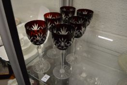 A set of six wine glasses with ruby tinted bowls.