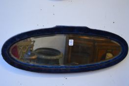 A pair of oval mirrors with blue velvet frames.