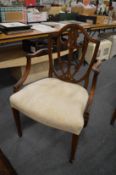 A set of eight Sheraton style mahogany dining chairs, two with arms, all with carved shield shaped