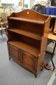 A mahogany open bookcase with a cupboard below.