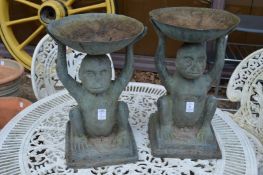 A pair of patinated metal plant stands modelled as seated monkeys holding dishes aloft.