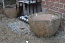 A large pair of concrete circular planters.