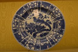 A Chinese blue and white circular plate decorated with a bird on a branch.