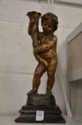 A carved painted gesso figure of a putti holding a cornucopia.