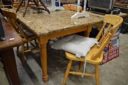 A granite topped kitchen table with a set of four kitchen chairs.