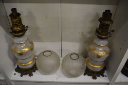 A pair of 19th century gilt decorated opaque glass oil lamps with etched shades (one shade