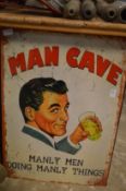 A novelty metal sign 'Man Cave'.