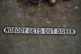 A novelty carved wood and painted sign 'Nobody Gets Out Sober'.