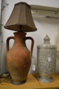 A terracotta twin handled lamp and another lamp base.