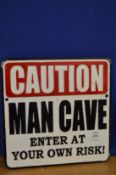A novelty cast iron man cave sign.