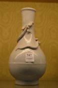 A Chinese pale celadon glazed bottle vase entwined with a dragon.