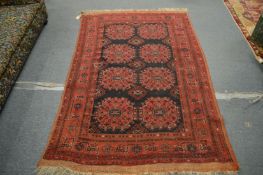 A Persian rug, red ground with two rows of four medallions, 200cm x 130cm.
