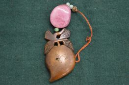 A Chinese signed carved rhino horn pendant with tourmaline and jade mounts.