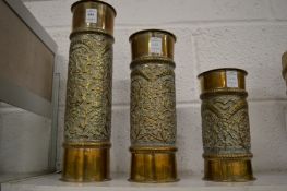 A graduated set of three embossed brass candle stands.