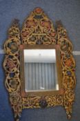 An ornate Eastern carved wood and polychrome decorated wall mirror.