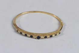 AN 18CT GOLD, SAPPHIRE AND DIAMOND BANGLE.