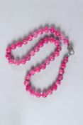 A GOOD STRING OF FORTY-SIX PINK JADE BEADS with diamond lock clasp.