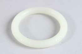 A CHINESE WHITE JADE CARVED BANGLE. 3.25ins diameter.
