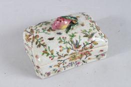 A RECTANGULAR PORCELAIN BOX AND COVER with peach handle. 7.5ins long.