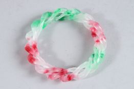 A CHINESE MULTI-COLOURED JADE TWIST BANGLE. 3.25ins diameter.