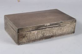 A LARGE PLAIN SILVER CIGARETTE BOX with crest. 8ins long. Birmingham 1909.