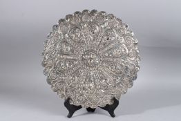 A LARGE EGYPTIAN SILVER CIRCULAR MIRROR with repousse and scroll decoration. 13ins diameter.