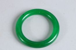 A PLAIN APPLE GREEN JADE BANGLE. 3.25ins diameter.